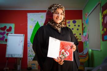 A young woman holding a red birthday card