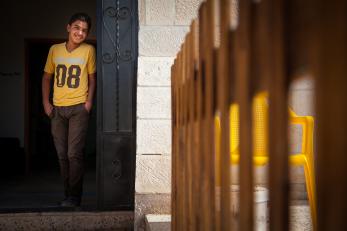 A boy wearing black pants and a yellow t-shirt that has the large numbers 08 on the front