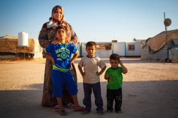 A woman standing with three young boys