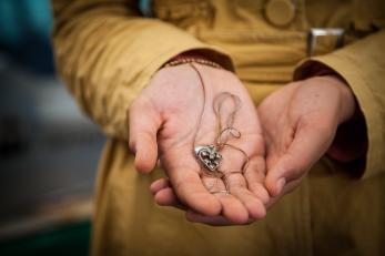 Hands holding a necklace with a heart pendant