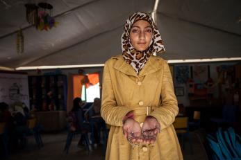 A teen girl in a yellow jacket holds a necklace in her hands