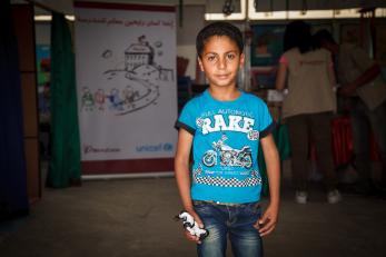 A boy in a blue t-shirt holds a small toy robot