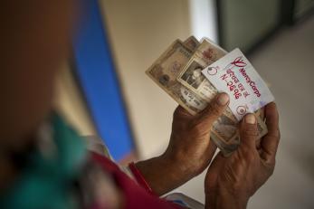 Image: Hands holding cash and a Mercy Corps ID card during a distribution of emergency cash