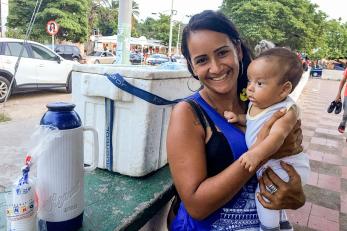 Elisa, a Venezuelan migrant to Colombia sells water and coffee in a park with her newborn child. Photo: Ana Maria Olarte/Mercy Corps