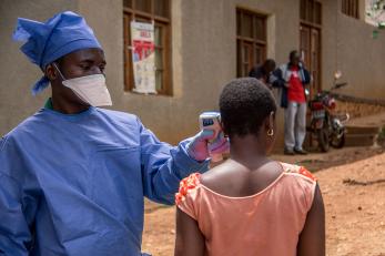 Habibu, hygienist at the Malepe Health Center in DRC, takes the temperature of every person who enters the health center after attending our training about preventing the spread of the Ebola virus epidemic. Photo: Rudy Nkombo/Mercy Corps