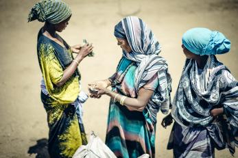 Three women are pictured. two are counting cash.