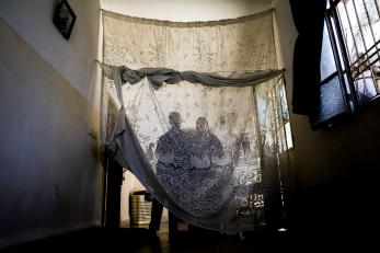 A family stands behind a sheer curtain in jordan, backlit by light coming through the window
