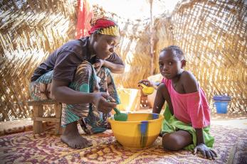 Mother and daughter in hut eating from bowl
