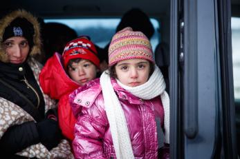 A young girl in a pink coat, hat and scarf