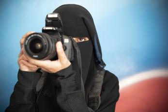 A woman holds a camera to her eye in Yemen