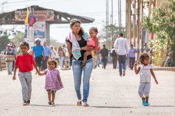 mother, baby, and young children walking down a road