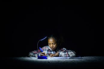 Lourdes writing by the light of a small lamp.