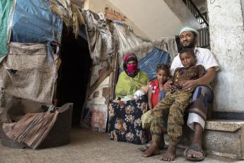 Yemeni family sitting together outside their home's entrance.