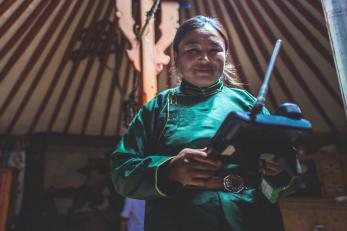 A Mongolian animal herder uses an SMS forecasting system device to monitor local weather.