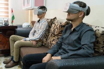 Two young participants in Iraq wear virtual reality goggles which provide visual and audial immersion.