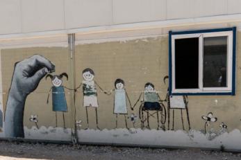 A wall painted with a mural of children holding hands.