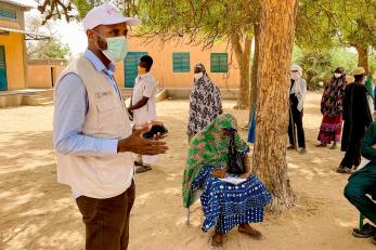 Participants in Tillaberi Region, Niger, listen to a Mercy Corps representative wearing a facemask explaining details about a program.