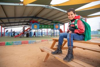 a young boy sitting at a playground in Jordan