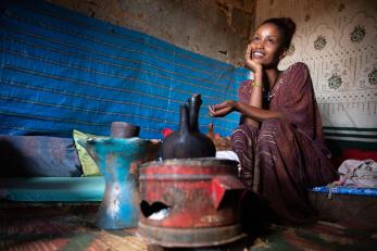 An adult sits and waits for coffee to brew inside her home in Ethiopia