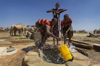Three young people work together to haul up water in Ethiopia.
