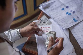 An adult invalidates a beneficiary's Mercy Corps ID card.