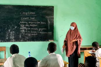 An instructor leads a class while standing at a chalk board.