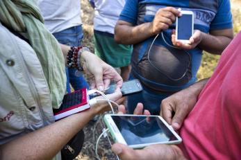 A group of people stand together and hold mobile devices.