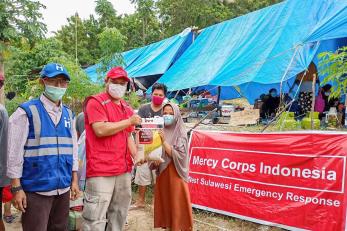 Humanitarian aid team members hand food to a participant.