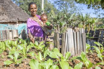 Timor Leste woman in vegetable garden with child.