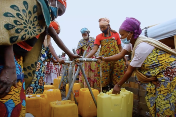 A group of people filling jerry cans at a water station.