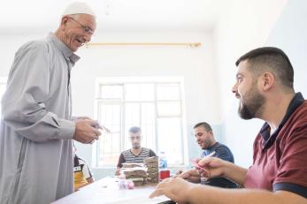 Hayder Shalash Aboudi, 62, receives a cash distribution from Mercy Corps. 