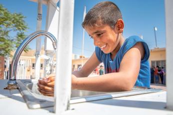 A young person washing their hands.