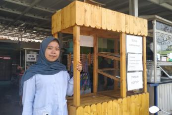 Nour Aulia standing next to her food kiosk business.