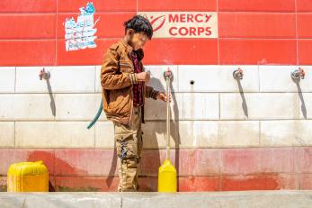 A young person fills a jerry can at a water point which was built by Mercy Corps.