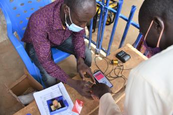 A Mercy Corps team member assists an e-voucher recipient with a digital identity process, increasing security and efficiency.