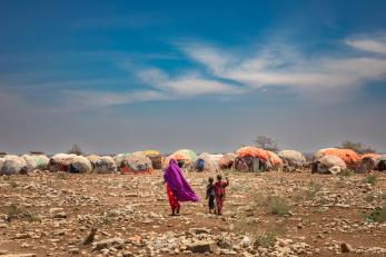 Two people walking towards temporary structures. 