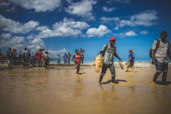 Mercy Corps staff and locals crossing flooded areas on foot.