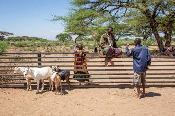 A person witting on a fence conversing with two other people. 