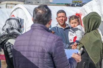 Adults with children speaking with aid workers about receiving emergency supplies.