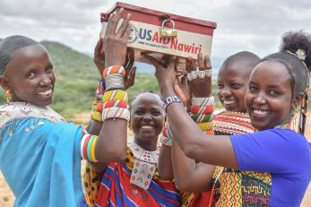 Four people holding up a locked box.