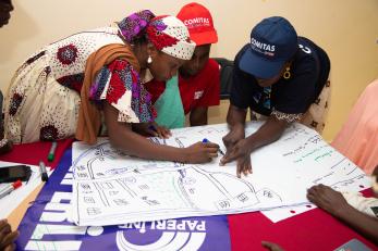Three people draw maps together on a table.