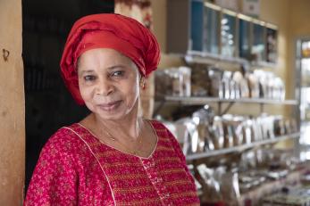 Senegalese female entrepreneur stands in her business smiling.