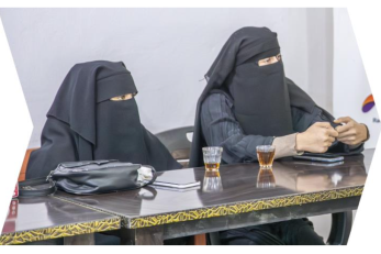Two Syrian woman site at a table in a meeting atmosphere.