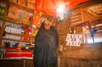Somalian woman displaying the lighting in her store.