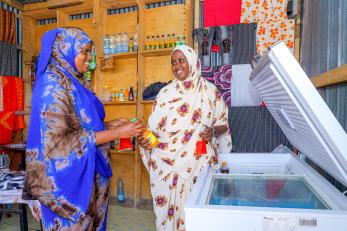 Two Kenyan women interact in a commercial environment.