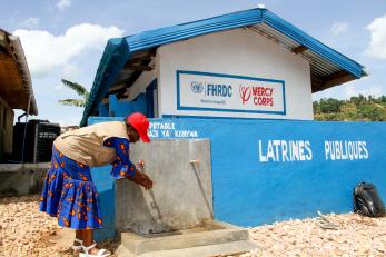A Congolese woman at a water point and latrine in North Kivu to strengthen hygiene and prevention.