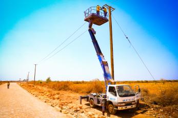 Electrification crew on lift-truck installing power lines outside Barwaaqo IDP settlement.
