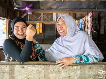 Two individuals laugh while posing for the camera.