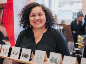 A vendor smiles at the camera from behind a display of their wares.