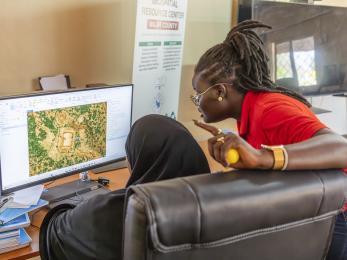 Two Kenyan women work in front of a computer together on a mapping program.